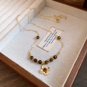 Detailed view of vintage tiger eye beaded necklace with a golden flower pendant