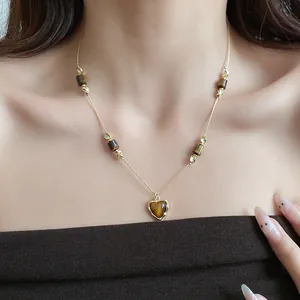 Detailed macro view of retro heart-shaped tiger eye stone pendant necklace on model