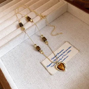 Detailed view of vintage gold necklace featuring tiger's eye beads and heart pendant