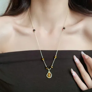 Detailed close-up of vintage tiger's eye beaded necklace with round pendant worn by model