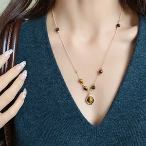 Close-up of tiger's eye beaded necklace with gold pendant on a female model