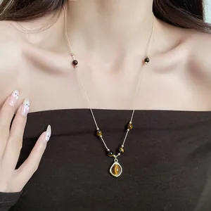 Elegant vintage tiger eye bead necklace with round pendant shown on female model neck