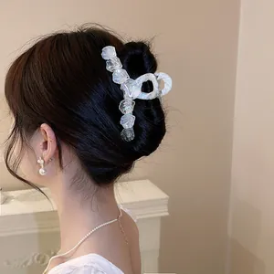 Detail view of elegant iridescent shell flower hair claw clip worn on a dark hair bun