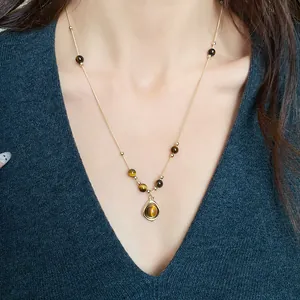 Detail shot of a vintage gold necklace featuring tiger eye beads and a round stone pendant.
