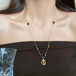 Close-up detail of vintage tiger eye bead necklace with round pendant on elegant model