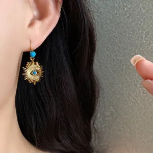 Elegant vintage sunburst gold earring with a turquoise eye bead detail worn by a model