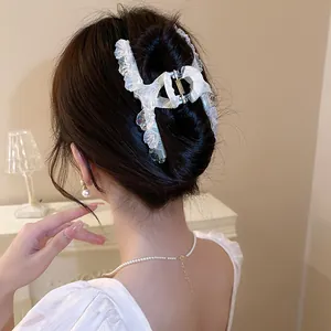 Iridescent shell-shaped hair claw clip with pearlescent finish worn by model