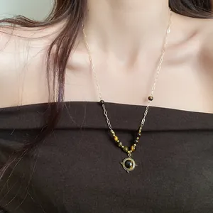 Detailed view of a vintage tiger eye bead round pendant necklace on a female model.