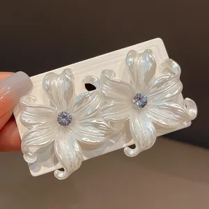 Elegante primer plano de pendientes de flores blancas nacaradas con centros de circonita