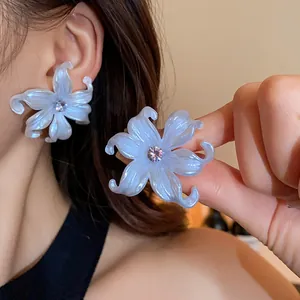 Detalle de los pendientes de botón con forma de flor de circonita azul claro en una modelo
