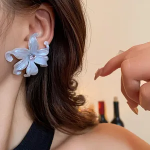 Primer plano de un elegante pendiente de flor de lirio blanco perla con centro de circón