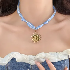 Detailed view of a retro stainless steel sun face pendant necklace with blue fabric cord.