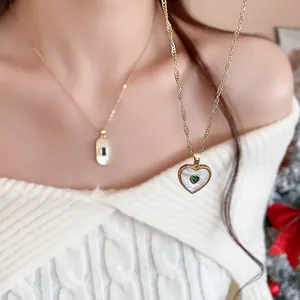 Detail showing heart-shaped gold necklace with white mother of pearl and green stone