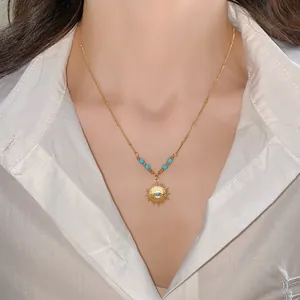 Detailed view of a gold sunburst necklace with turquoise center on a model's neck