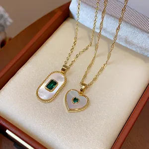 Close-up of gold-plated heart and oval necklaces with white mother-of-pearl and green gems