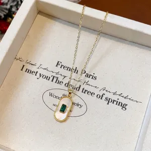 Close-up of elegant gold-plated necklace with emerald and mother-of-pearl pendant