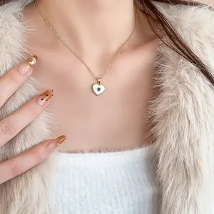 Detailed view of a gold-plated heart necklace with mother-of-pearl and green stone