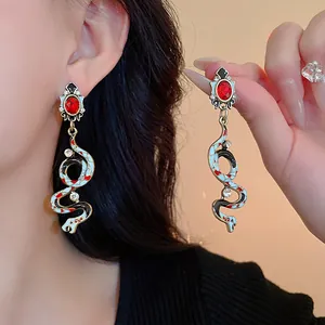 Close-up detail of vintage serpent drop earrings with red stones and enamel patterns