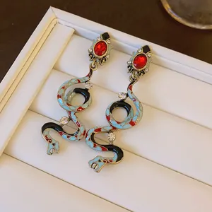 Detailed macro view of vintage snake earrings with red gems and light blue enamel