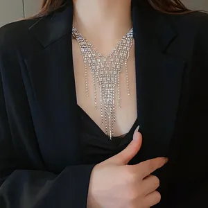 Detail view of an elegant silver rhinestone fringe necklace worn over a black blazer.
