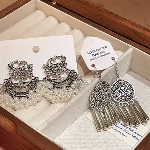 Detailed view of ethnic style phoenix and tassel earrings in a wooden jewelry box.