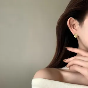 Close-up of model wearing circular hammered 18k gold plated earrings on the ear