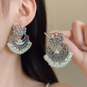 Detailed macro view of vintage ethnic peacock earrings with white pearl tassels