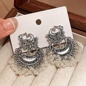 Detailed macro view of retro ethnic style peacock earrings with white pearl tassels