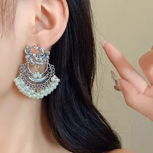 Detailed view of ethnic phoenix silver earrings with white pearl tassels on model