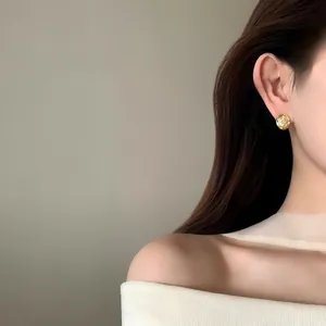 Elegant 18K gold plated textured round clip-on earrings for women worn by a model.