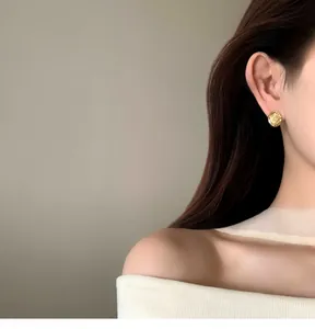 Elegant 18k gold plated round textured stud earring shown worn on ear for detail