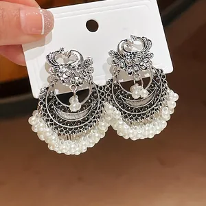 Close-up of vintage ethnic phoenix earrings with silver finish and white pearl fringe detail