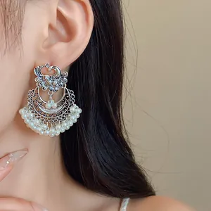 Detailed view of ethnic phoenix drop earrings featuring circular frames and white pearl tassels
