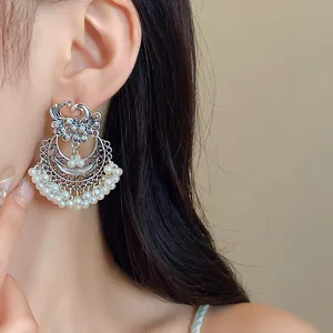 Close-up of ethnic phoenix earrings with silver filigree and white pearl tassels