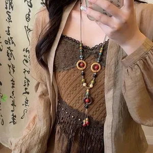 Lange vintage etnische kralenketting met geometrische cirkels en kwastje op model