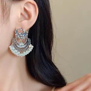 Close-up detail of vintage ethnic silver phoenix earrings with white pearl tassels