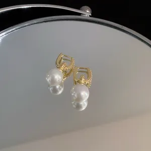 Detailansicht eleganter vergoldeter Perlenohrringe, die sich im Spiegel spiegeln
