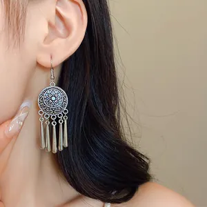 Close-up of vintage ethnic silver earrings with phoenix engraving and metallic tassels