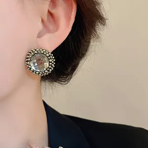 Macro view of vintage court-style circular flower stud earrings worn on a model ear