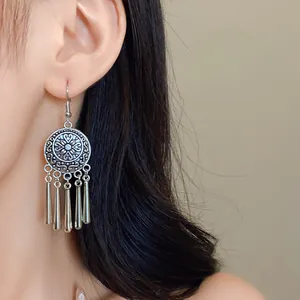Detailed macro view of vintage silver ethnic tassel earrings with intricate circular medallion