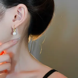 Nahaufnahme eleganter goldener Creolen mit kleinen Kristallen und einer weißen Perle