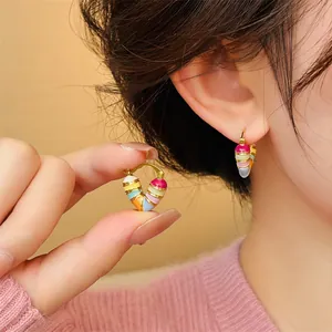 Detailed macro view of colorful heart-shaped enamel hoop earrings worn by model