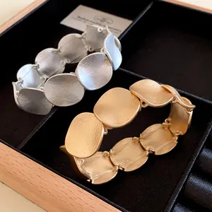 Nahaufnahme von strukturierten Metallarmbändern in Gold und Silber in Schmuckschatulle.