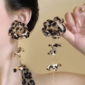 Dettaglio macro degli orecchini vintage a fiore leopardato con eleganti catene dorate.