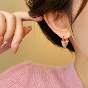 Detailed macro view showing colorful enamel heart hoop earrings on a model's ear