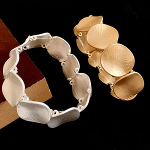 Detailansicht goldener und silberner Metallarmbänder mit strukturierter Oberfläche