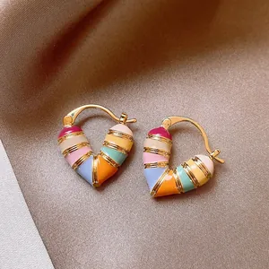 Close-up detail of colorful enamel heart hoop earrings featuring vibrant geometric patterns