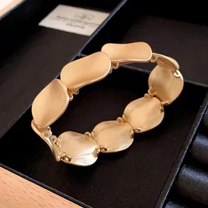 Nahaufnahme eines mattgoldenen, strukturierten Metallarmbands in einer Schmuckschatulle