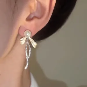 Primo piano di eleganti orecchini a fiocco con perle e nappe scintillanti.