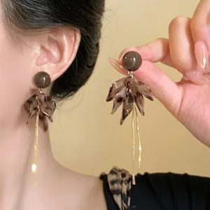 Dettaglio delle orecchie con orecchini vintage a petalo leopardato e catenine dorate